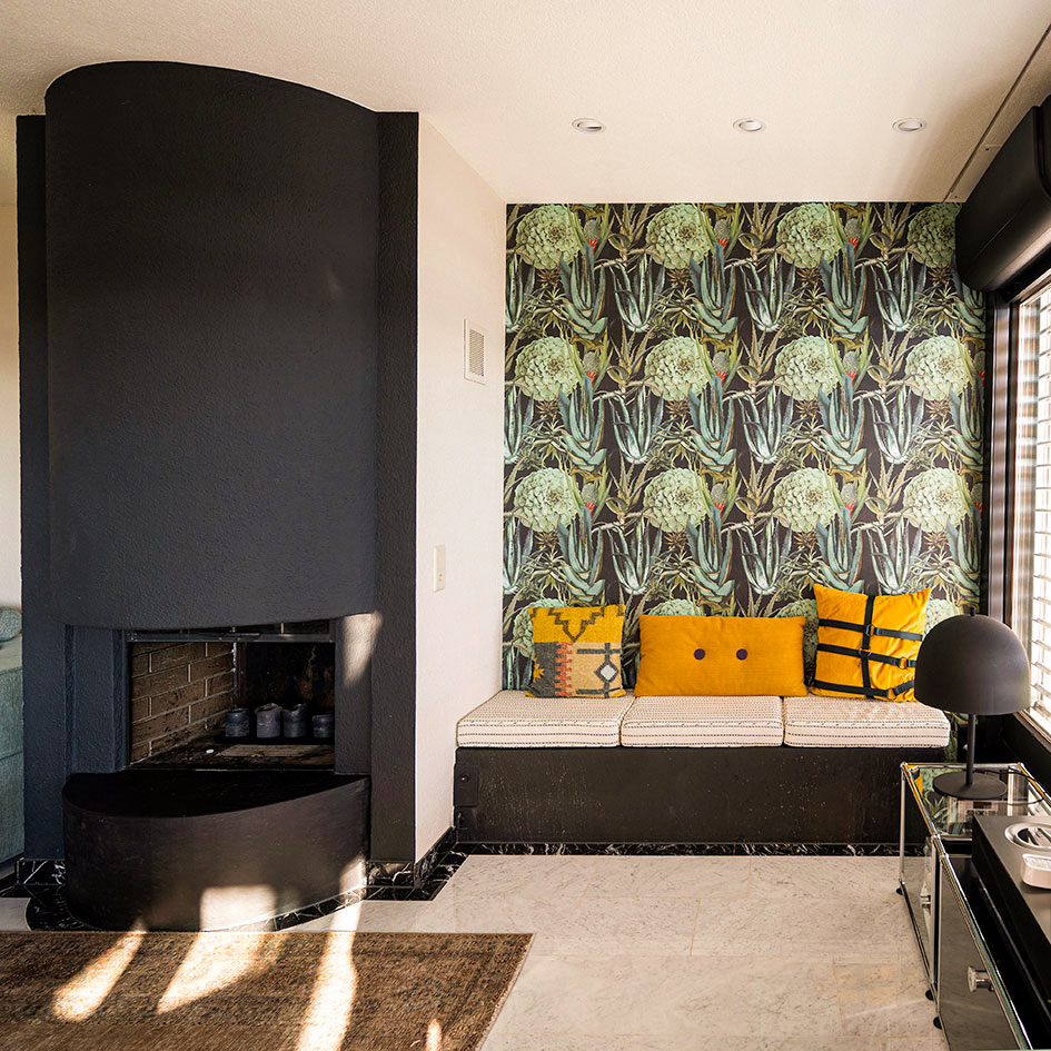 Ein elegantes Wohnzimmer im Midcentury-Stil, das mit einer auffälligen floralen Tapete als zentrales Designelement versehen ist. Das Interiordesign kombiniert die ikonischen Linien und Formen des Midcentury-Designs mit modernen Akzenten, wobei das Farbdesign und Farbkonzept in harmonischen, aber lebendigen Tönen aufeinander abgestimmt sind. Die florale Tapete bringt nicht nur Textur, sondern auch einen frischen, natürlichen Akzent in den Raum, der das Inneneinrichtungs- und Interiorkonzept perfekt ergänzt. Durch den gezielten Einsatz von Akzenten wird die florale Tapete zum Highlight, das dem Raum Tiefe und Charakter verleiht, während das Gesamtbild ruhig und ausbalanciert bleibt.