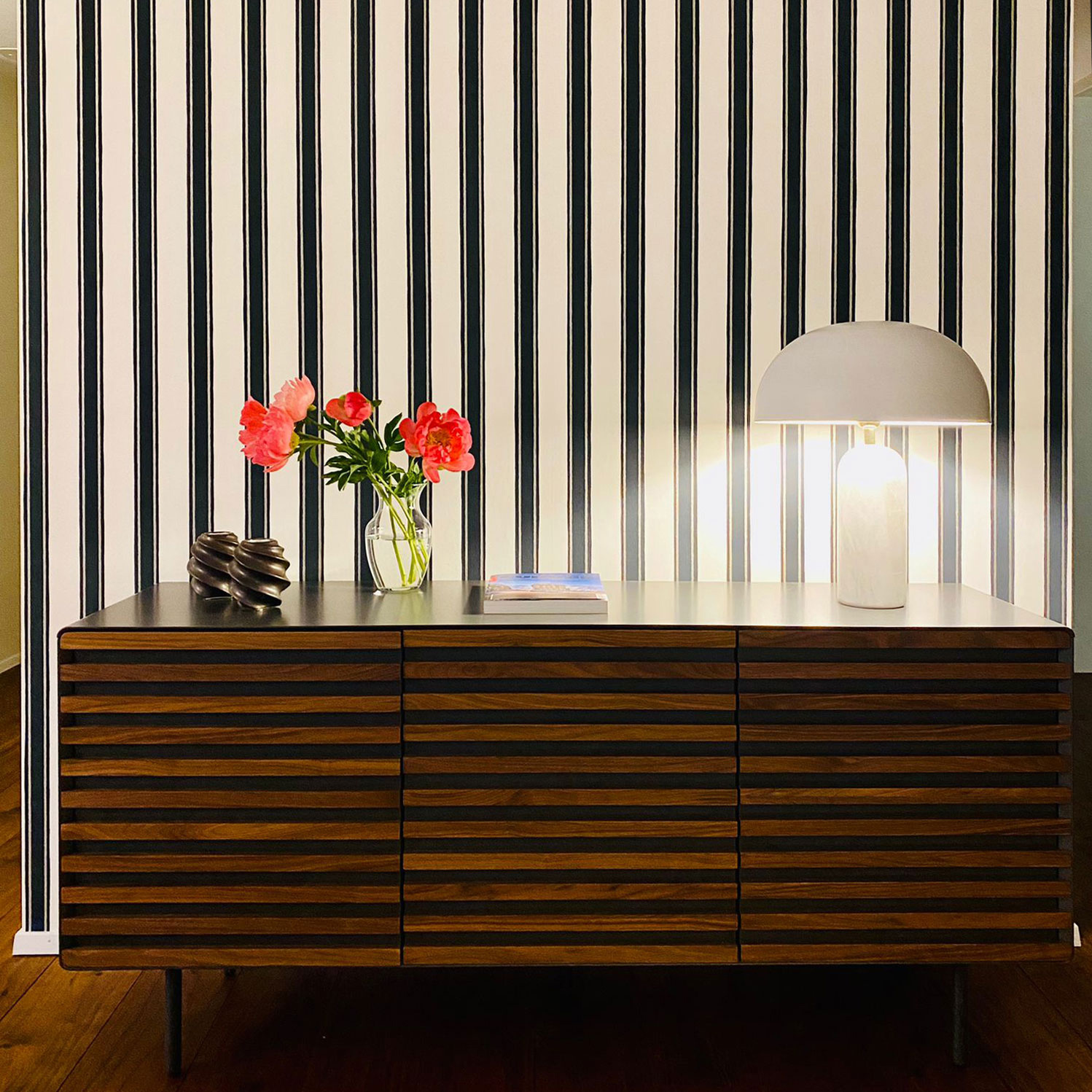 Ein raffiniertes Interiordesign, das mit einer eleganten Streifentapete von Farrow & Ball im Mittelpunkt beeindruckt. Das Farbkonzept und Farbdesign wurden sorgfältig ausgewählt, um eine harmonische Balance zwischen klassischen und modernen Elementen zu schaffen. Die Streifentapete bringt Struktur und Textur in den Raum, während die Farben des Designs das Ambiente mit Eleganz und Stil bereichern. Dieses Farbkonzept verleiht dem Raum eine zeitlose Schönheit, die durch die subtile Kombination von hellen und dunklen Tönen verstärkt wird, was dem Raum eine warme und zugleich edle Atmosphäre verleiht.